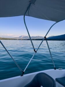 Peaceful boat ride on a lake with stunning mountain views under a clear blue sky.