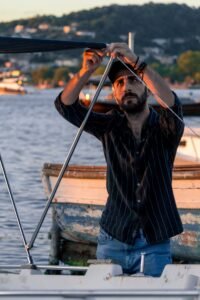 Man adjusting boat canopy in marina at sunset. Relaxed maritime scene.