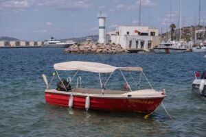 Charming harbor scene in Foça, Turkey featuring boats, a lighthouse, and clear skies.